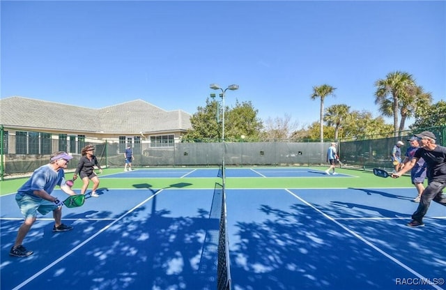 view of tennis court featuring community basketball court and fence