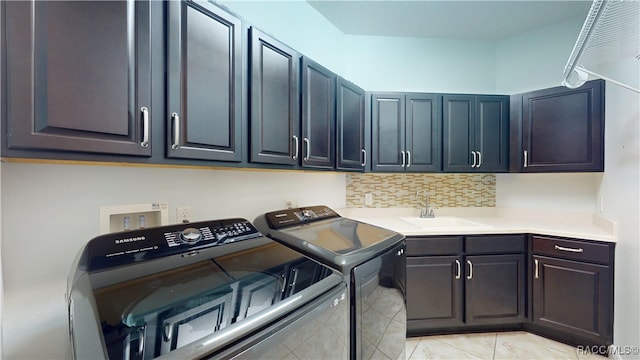 clothes washing area featuring cabinet space, a sink, and washing machine and clothes dryer