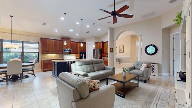 living area featuring light tile patterned flooring, visible vents, arched walkways, and ceiling fan with notable chandelier