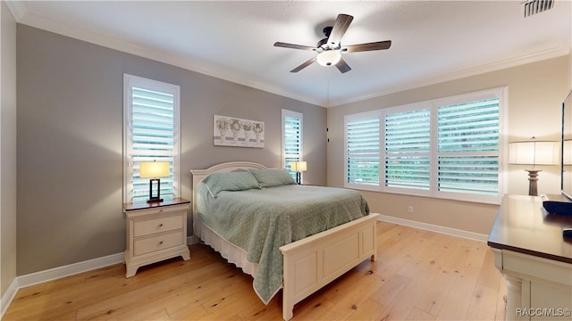 bedroom with light wood-style floors, baseboards, visible vents, and ornamental molding