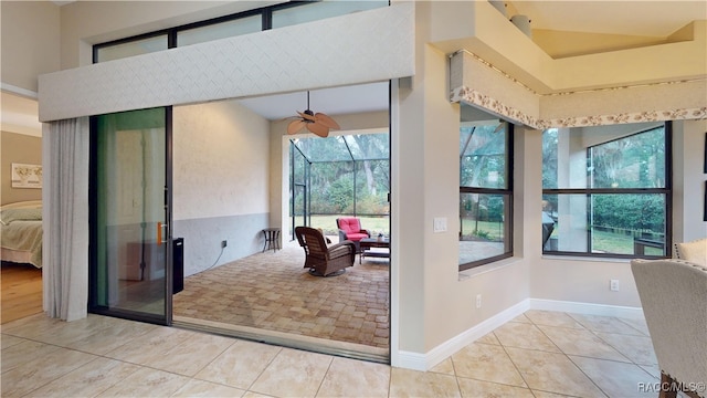 doorway to outside with light tile patterned floors, a sunroom, and baseboards