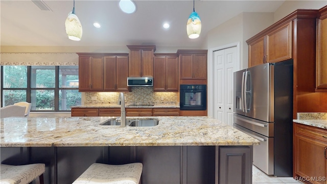 kitchen with black appliances, a breakfast bar, a sink, and pendant lighting