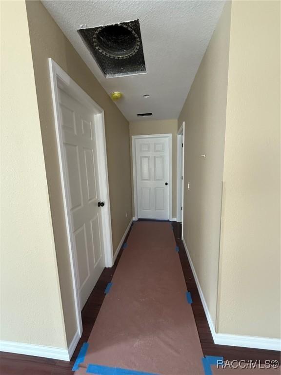 corridor featuring dark hardwood / wood-style floors and a textured ceiling