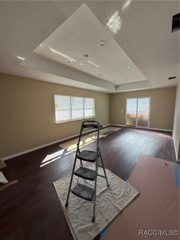 spare room with dark hardwood / wood-style floors and a raised ceiling