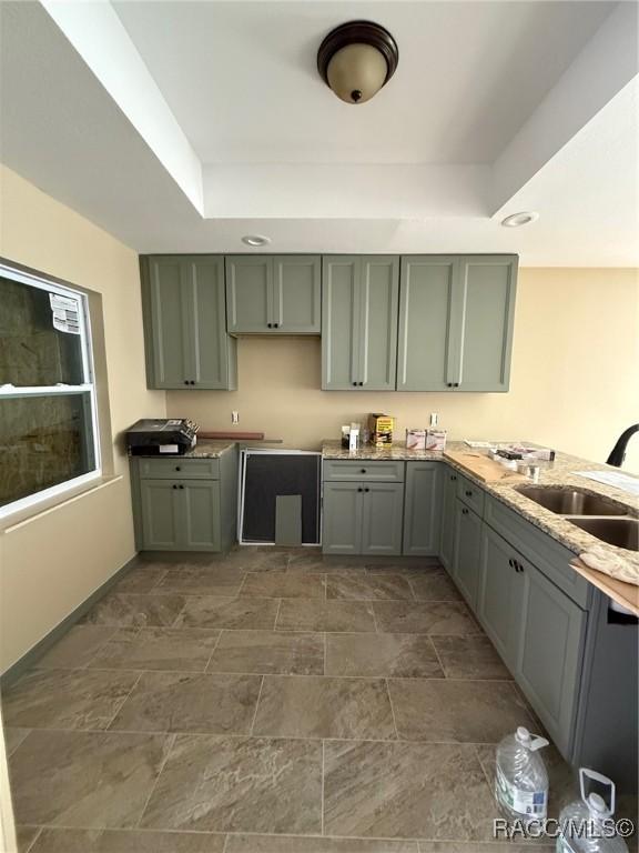 kitchen featuring a raised ceiling and sink