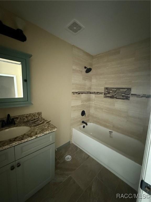 bathroom featuring tiled shower / bath and vanity