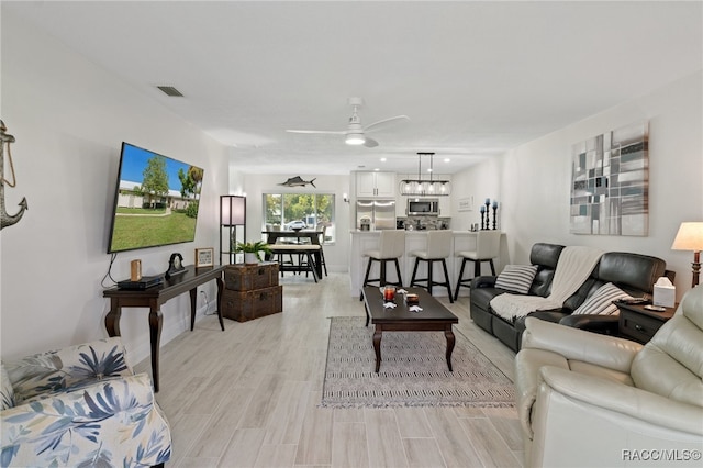 living room with ceiling fan and light hardwood / wood-style flooring