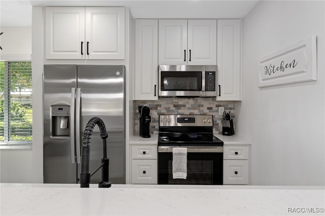 kitchen with white cabinets, appliances with stainless steel finishes, and tasteful backsplash