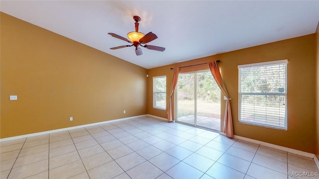 empty room featuring vaulted ceiling, light tile patterned floors, baseboards, and ceiling fan