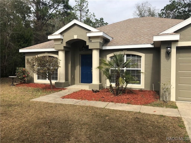 view of front of house featuring stucco siding and a shingled roof