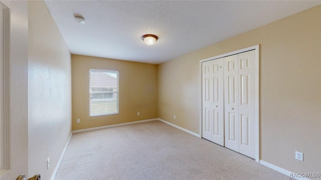 unfurnished bedroom with a closet, baseboards, a textured ceiling, and carpet flooring