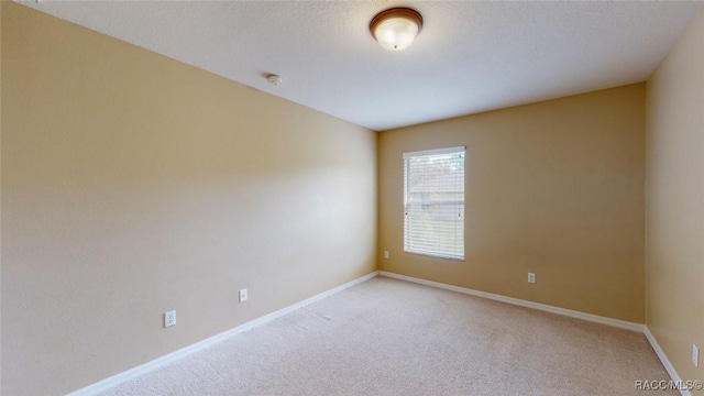 unfurnished room with baseboards, light carpet, and a textured ceiling