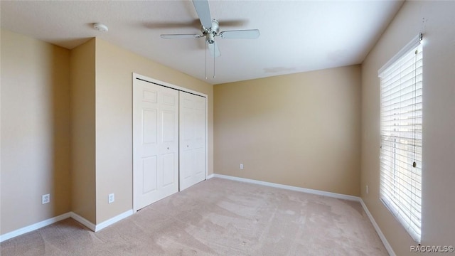 unfurnished bedroom with a closet, multiple windows, light carpet, and baseboards