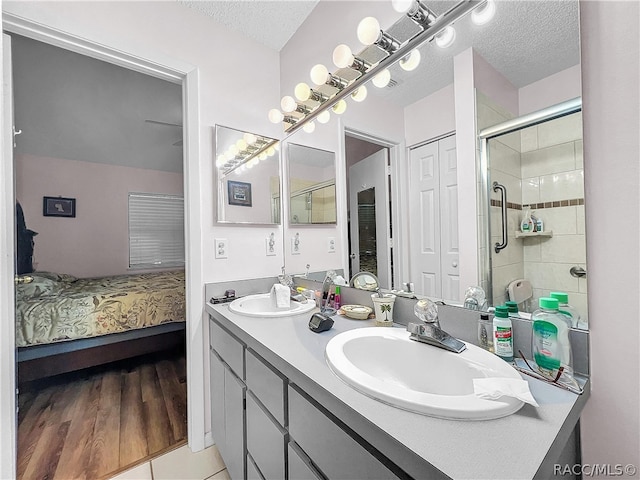 bathroom featuring vanity, a shower with shower door, a textured ceiling, and hardwood / wood-style flooring