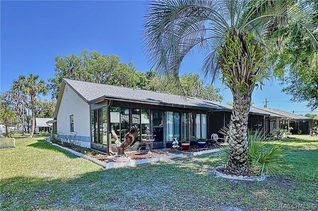 rear view of property with a lawn and a sunroom