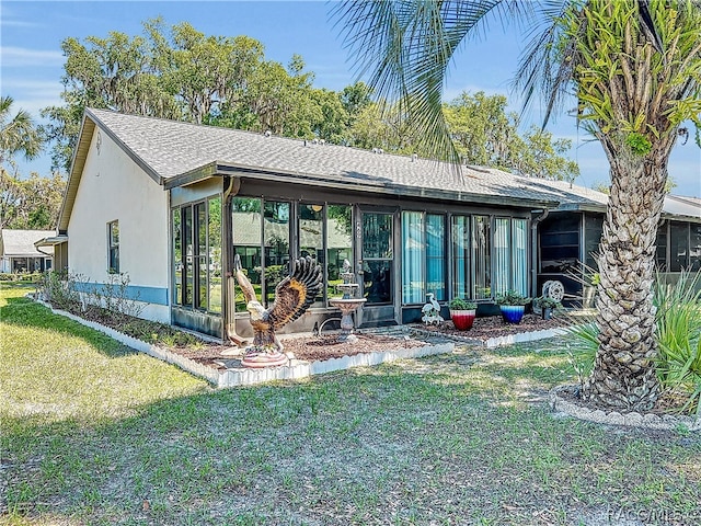 rear view of house featuring a yard and a sunroom