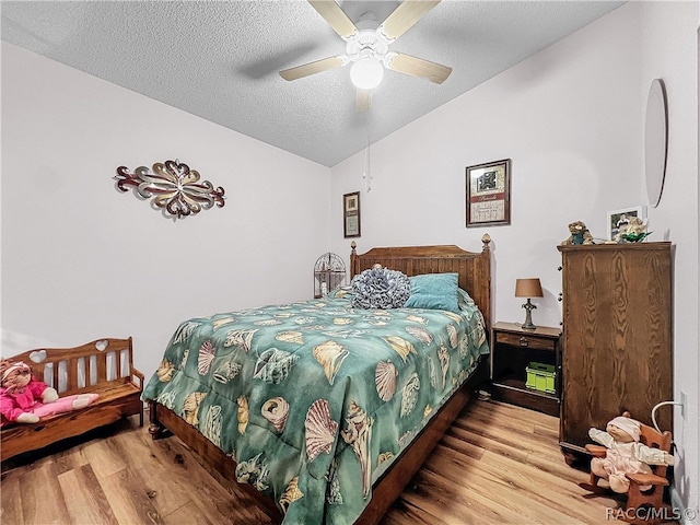 bedroom with hardwood / wood-style floors, ceiling fan, lofted ceiling, and a textured ceiling