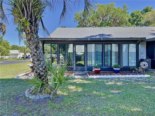 rear view of property featuring a sunroom, cooling unit, and a yard