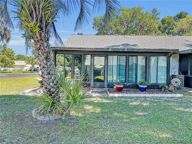 back of property with a sunroom, a yard, and cooling unit