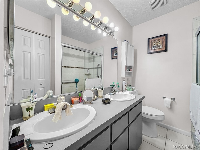 bathroom with tile patterned floors, walk in shower, vanity, a textured ceiling, and toilet