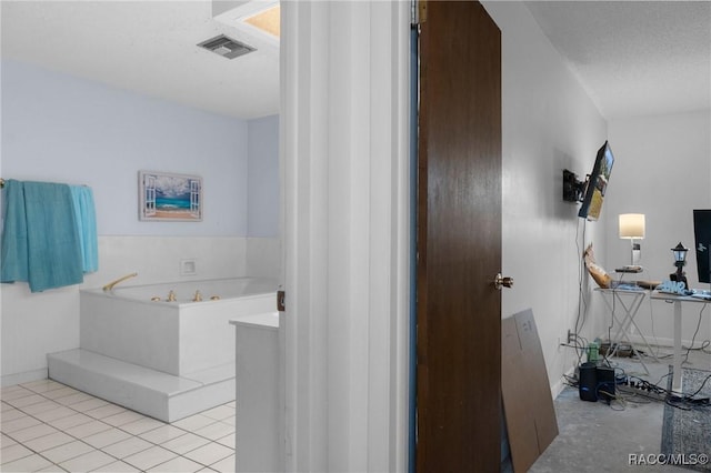 bathroom with a washtub, tile patterned flooring, and a textured ceiling