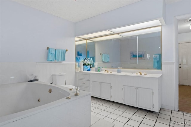 bathroom featuring a bathtub, vanity, a textured ceiling, tile patterned floors, and toilet