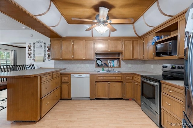 kitchen with appliances with stainless steel finishes, sink, a kitchen bar, kitchen peninsula, and light wood-type flooring