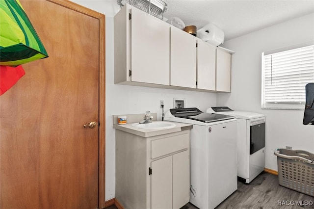 laundry room featuring washer and clothes dryer, light hardwood / wood-style flooring, cabinets, and sink