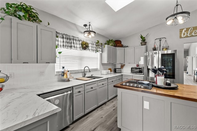 kitchen featuring sink, stainless steel appliances, light hardwood / wood-style flooring, butcher block countertops, and decorative light fixtures