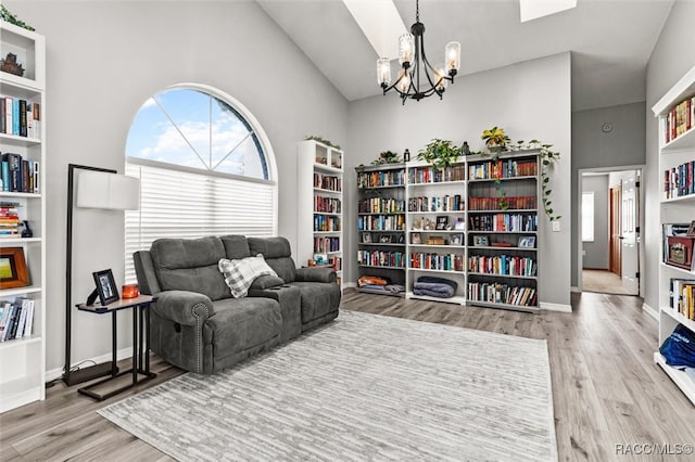 living area featuring vaulted ceiling, an inviting chandelier, and light hardwood / wood-style flooring