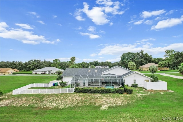 rear view of property with a yard, glass enclosure, and a swimming pool