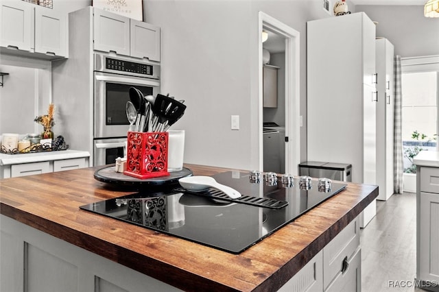 kitchen with black electric cooktop, white cabinets, wooden counters, and light hardwood / wood-style floors