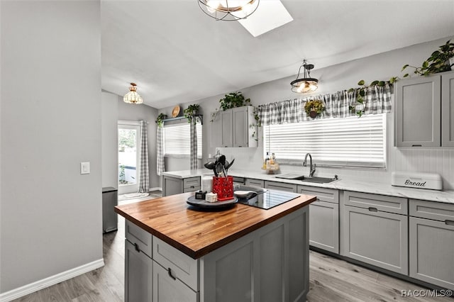 kitchen featuring gray cabinetry, sink, pendant lighting, a kitchen island, and light wood-type flooring