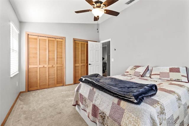 bedroom with two closets, ceiling fan, light carpet, and vaulted ceiling