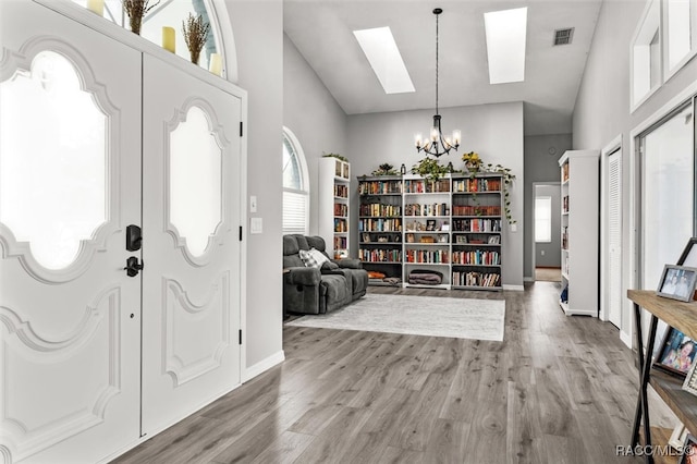 entrance foyer with hardwood / wood-style floors, high vaulted ceiling, and a notable chandelier