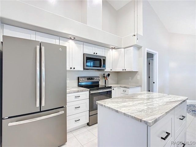 kitchen featuring light stone counters, a kitchen island, white cabinets, appliances with stainless steel finishes, and light tile patterned flooring