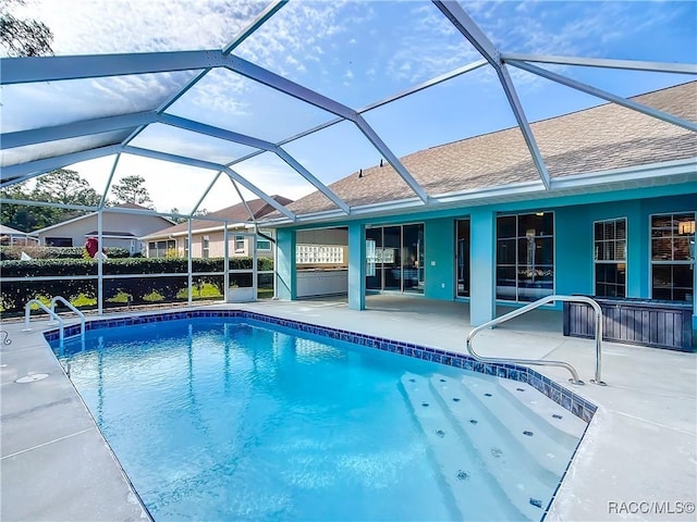 view of pool with glass enclosure and a patio