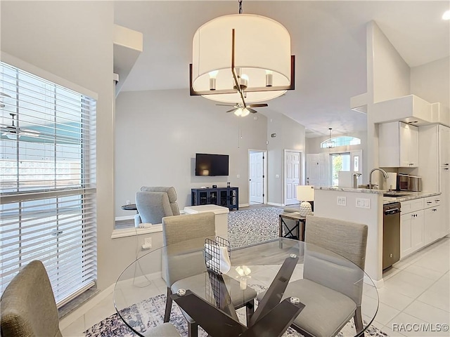 dining area with sink, high vaulted ceiling, ceiling fan with notable chandelier, and light tile patterned floors