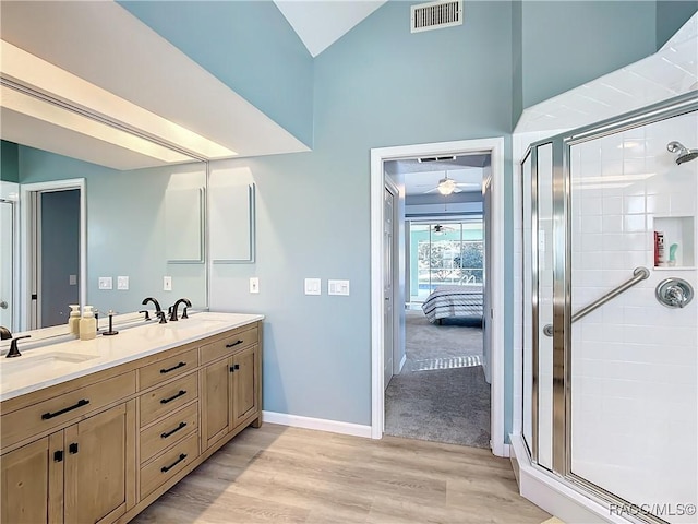 bathroom with wood-type flooring, vanity, a shower with shower door, and vaulted ceiling