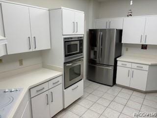 kitchen with white cabinets, light tile patterned floors, and stainless steel appliances