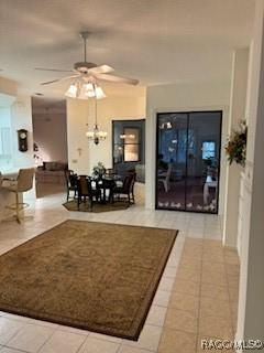 tiled living room with ceiling fan with notable chandelier