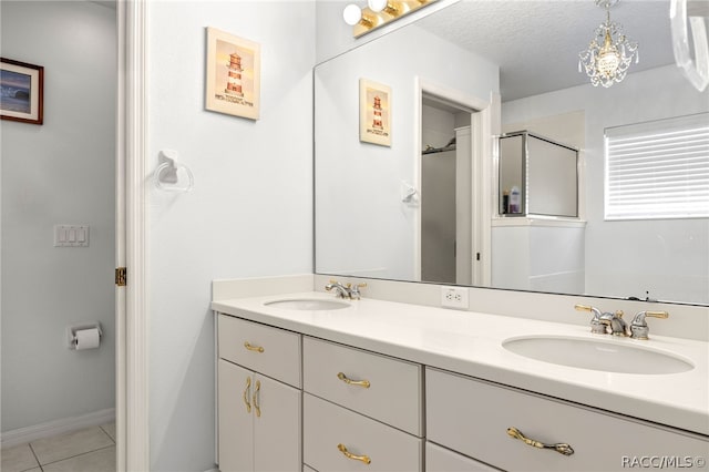 bathroom with tile patterned flooring, vanity, an enclosed shower, and a textured ceiling