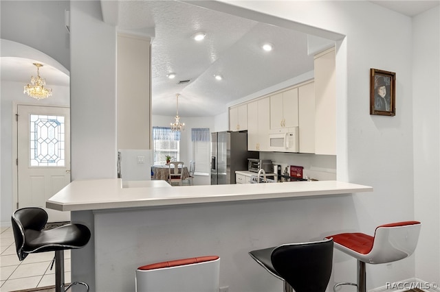 kitchen featuring kitchen peninsula, a wealth of natural light, an inviting chandelier, and appliances with stainless steel finishes