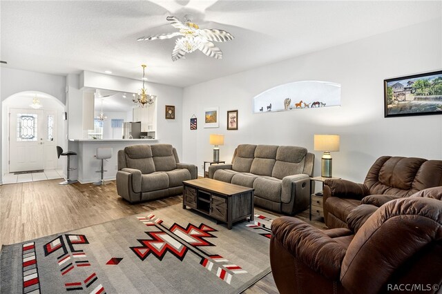 living room with ceiling fan with notable chandelier and light wood-type flooring