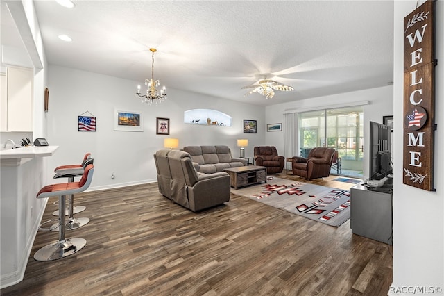 living room featuring a textured ceiling, ceiling fan with notable chandelier, and dark hardwood / wood-style floors