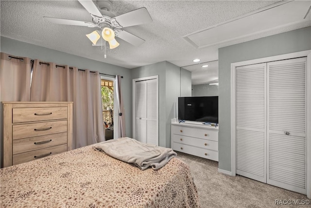 carpeted bedroom with two closets, a textured ceiling, a ceiling fan, recessed lighting, and attic access