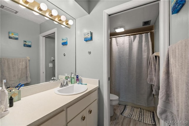 bathroom with vanity, visible vents, toilet, and wood finished floors