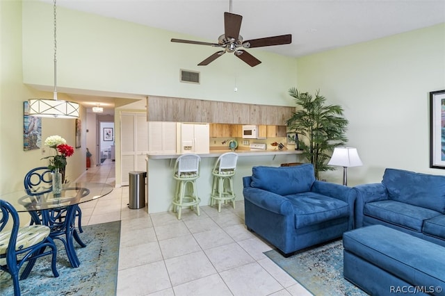 tiled living room with ceiling fan and high vaulted ceiling