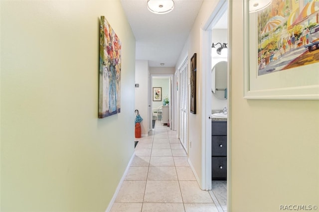 hall featuring light tile patterned floors and sink