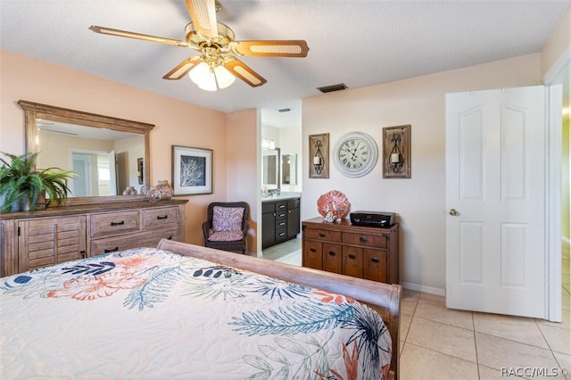 bedroom with ceiling fan, light tile patterned flooring, a textured ceiling, and connected bathroom